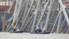 Barcos de la policía trabajan alrededor de un carguero atrapado bajo una parte de la estructura del puente Francis Scott Key, el miércoles 27 de marzo de 2024, en Baltimore, un día después de que el carguero chocó contra una columna del puente y causó su derrumbe. 