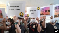 FILE - Supporters of a Hong Kong journalist fined for accessing a public database for an investigative report hold placards outside a court in Hong Kong, April 22, 2021. 