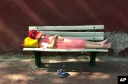 بیجنگ کی ایک سڑک پر کچھ دیر نیند کرنے والی ایک خاتون، فائل فوٹو)