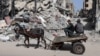 Palestinci na zaprežnom vozilu koje vuče magarac prolaze pored zgrade uništene u izraelskom bombardovanju, na jugu Pojasa Gaze, 31. marta 2024.