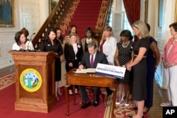 North Carolina Democratic Gov. Roy Cooper signs an executive order designed to protect abortion rights in the state at the Executive Mansion in Raleigh, N.C. on Wednesday, July 6, 2022. The order in part prevents the extradition of a woman who receives an abortion in North Carolina but may live in another state where the procedure is barred. (AP Photo/Gary D. Robertson).