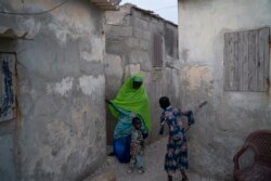 Ndeye Yacine Dieng talks with her 3-year-old grandson Babacar as she arrives at her home in Bargny, Senegal some 35 kilometers (22 miles) east of Dakar, Senegal, Wednesday April 21, 2021.