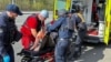 Policajci i medicinski radnici lzbrinjavaju ranjenog lokalnog stanovnika nakon ruskog zračnog napada, u Harkovu, Ukrajina, 9. aprila 2024.