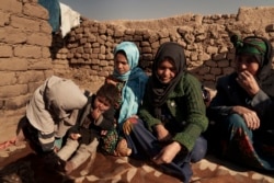 Aziz Gul, second from right, and her 10-year-old daughter Qandi, center, sit outside their home with other family members, near Herat, Afghanistan. Dec. 16, 2021. Qandi's father sold her into marriage without telling his wife, Aziz.