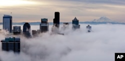 Downtown buildings rise above a low-level morning fog as Mount Rainier is seen some 80 miles distant, Jan. 9, 2015, in this view from atop the Space Needle in Seattle.