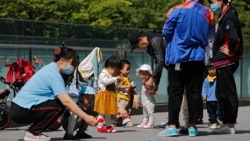Residents bring their children to play in a compound near a commercial office building in Beijing on May 10, 2021. (AP Photo/Andy Wong)