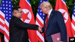 FILE - In this June 12, 2018, file photo, North Korea leader Kim Jong Un, left, and U.S. President Donald Trump shake hands at the conclusion of their meetings at the Capella resort on Sentosa Island in Singapore. 
