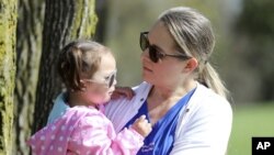 FILE - In this April 23, 2019 photo, Lisa Kum is seen in a park near Madison, Wis., with her daughter Emma, 2. In 2014, Kums husband Sothy Kum allowed an acquaintance to pay him to send marijuana to his house.