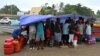 Voters and their families shelter from the rain while waiting to board small boats to vote in their provinces, in the capital Honiara, Solomon Islands, April 16, 2024.
