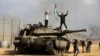 ARCHIVO - Los palestinos ondean su bandera nacional y celebran junto a un tanque israelí destruido en la valla del sur de la Franja de Gaza, al este de Khan Younis, el sábado 7 de octubre de 2023, el día de los ataques de Hamás contra Israel.