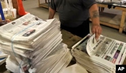 FILE - An employee sorts newspapers for delivery at a distribution center in Liberty Township near Youngstown, Ohio, on Aug. 6, 2019. (AP Photo/Tony Dejak, File)