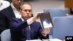 Israeli Ambassador to the UN Gilad Erdan shows a video of drones and missiles heading toward Israel during a United Nations Security Council meeting on the situation in the Middle East, including Iran's recent attack against Israel, at UN headquarters in