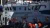 Des agents des forces frontalières britanniques transfèrent des migrants interceptés voyageant entre la France et Douvres, a bord d'un navire de patrouille dans le sud-est de l'Angleterre, le 13 août 2020. (Photo Ben STANSALL / AFP)