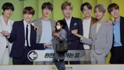 A woman wearing a face mask to help protect against the spread of the coronavirus walks by a board showing members of South Korean K-Pop group BTS to advertise a local bank's money exchange in Seoul, South Korea, Wednesday, Sept. 30, 2020. (AP Photo…