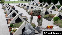 Грузинская военнослужащая возлагает цветы к могиле солдата во время церемонии на кладбище в Тбилиси.