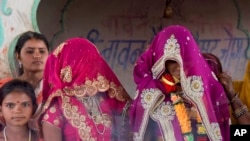 An underaged bride, right, stands with family members during her marriage at a Hindu religious building near Rajgarh, Madhya Pradesh state, India, April 17, 2017. (AP Photo/Prakash Hatvalne)