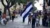 Un joven nicaragüense sostienen una bandera de Nicaragua mientras camina por una calle en San José, el 20 de septiembre de 2021. 