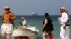 (FILE) Pria bersenjata di pantai sementara kapal komersial yang disita oleh Houthi, berlabuh di lepas pantai.