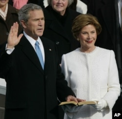 FILE - President Bush takes the oath of office with First Lady Laura Bush at his side, 2005. (AP Photo/Paul Sancya)