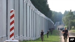 Польские пограничники у защитного сооружения, воздвигнутого Польшей вдоль границы с Беларусью для защиты от нелегальной миграции. 30 июня 2020 