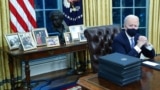 Biden family photos are displayed around a bust of activist Cesar Chavez, as U.S. President Joe Biden prepares to sign executive orders at the Resolute Desk inside the Oval Office of the White House in Washington, U.S., January 20, 2021. Picture taken Jan