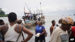 Fishmongers from Limbe, Cameroon, and neighboring communities wait at the shore for fishing boats to arrive with their catch at the shore on Limbe, on April 12, 2022. (AP Photo/Grace Ekpu)
