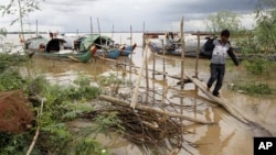 一名柬埔寨人7月27日从他停泊在金边郊外湄公河上的渔船走上岸