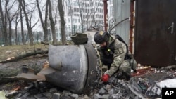 FILE - A Ukrainian police officer inspects a rocket part near a residential building damaged by a Russian missile strike in Kharkiv, Ukraine, Tuesday, Jan. 2, 2024.