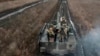 En esta fotografía tomada de un vídeo publicado por el Servicio de Prensa del Ministerio de Defensa ruso el sábado 13 de abril de 2024, soldados rusos viajan en su vehículo blindado para tomar posiciones y disparar hacia posiciones ucranianas en un lugar no revelado en Ucrania. 