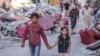 (FILE) Seorang anak laki-laki dan anak perempuan Palestina bergandengan melalui gedung-gedung yang hancur di Jalur Gaza.