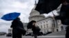 Un cierre del gobierno de EEUU continúa como una amenaza al enfrascarse discusiones entre republicanos y demócratas sobre el nivel de gasto. Un grupo de personas son captadas en las afueras del Capitolio en Washington capeando un fuerte viendo y lluvia el 27 de febrero de 2024.