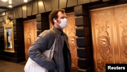 FILE - A man in a protective mask walks past a closed theatre after it was announced that Broadway shows will cancel performances due to the coronavirus outbreak in New York, U.S., March 12, 2020. (REUTERS/Mike Segar/File Photo)