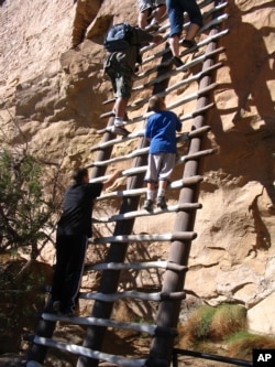 Visitors climb steep ladders on a tour of Balcony House, an ancient cliff dwelling in Mesa Verde National Park
