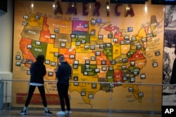 FILE - Travelers look over a map of the United States in the terminal of Denver International Airport, Friday, Dec. 24, 2021, in Denver. Denver is one city that has attracted young white adults. (AP Photo/David Zalubowski)