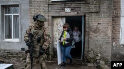 Члени місцевої виборчої комісії та озброєний військовий відвідують виборців на російських президентських виборах в окупованому Донецьку