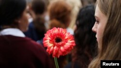 A student holds a flower during a vigil to commemorate victims of Friday's shooting, outside Masjid Al Noor mosque in Christchurch, New Zealand March 18, 2019.