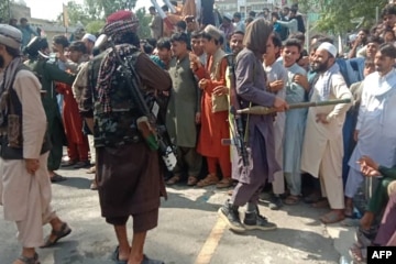 Ilustrasi helikopter AS terbang, dengan tentara Taliban duduk di tank AS yang terlantar dan dikelilingi oleh bunga poppy merah.