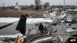 Жители украинского Бахмута пытаются пройти по разрушенному мосту. 1 февраля 2023г. 