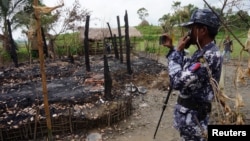FILE - A Myanmar border guard police officer takes pictures at the remains of a burned house in Tin May village, northern Rakhine state, Myanmar July 13, 2017.