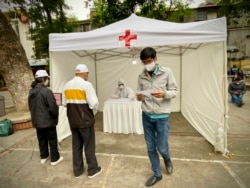 People receive test results at a makeshift COVID-19 testing facility in Hanoi, Vietnam on Tuesday, Mar.31, 2020. Vietnam has set up its first makeshift facilities for fast coronavirus testing in residential areas in an effort to detect early infections.