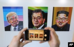 FILE - A visitor takes images, from left, of U.S. President Donald Trump, South Korean President Moon Jae-in and North Korean leader Kim Jong Un during an exhibition at an annex of the presidential Blue House in Seoul, South Korea, Jan. 3, 2019.
