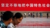人們走過北京天安門廣場豎立的一幅宣傳中國特色社會主義道路的巨幅標語。 （2012年6月3日）
