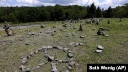 In this Wednesday, July 24, 2019, photo, a flat piece of ground and rock cairns are all that remain of the stage of the 1969 Woodstock Music and Arts Fair in Bethel, New York.