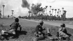 Cambodian soldiers await the end of an airstrike by U.S. planes in the background before advancing toward a palm grove off route 4, south of Phnom Penh, June 13, 1973. (AP photo)