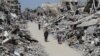 Palestinians walk past the ruins of houses and buildings destroyed during Israel’ military offensive, in the northern Gaza Strip