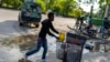 Un vendedor ambulante empuja su carrito frente al Palacio Nacional mientras un coche de policía blindado patrulla la zona, en Puerto Príncipe, Haití, el martes 23 de abril de 2024.