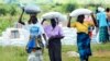 FILE - Women carry bags of maize during a food aid distribution in Mudzi about 230 kilometres northeast of the capital Harare, Zimbabwe, Feb. 20, 2020.