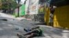 สตรีรายหนึ่งเดินผ่านร่างชายที่ถูกยิงเสียชีวิตในกรุงปอร์โตแปรงซ์ เมืองหลวงของเฮติ วันที่ 28 มีนาคม 2024