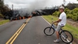 FILE - Hawaii resident Sam Knox watches the lava stretch across the road, Saturday, May 5, 2018, in Pahoa, Hawaii. (AP Photo/Marco Garcia)