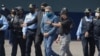 ARCHIVO - El expresidente hondureño Juan Orlando Hernández, en el centro, es llevado esposado a un avión al ser extraditado a Estados Unidos para enfrentar cargos de tráfico de drogas en una base de la Fuerza Aérea en Tegucigalpa, Honduras, el 21 de abril de 2022. 